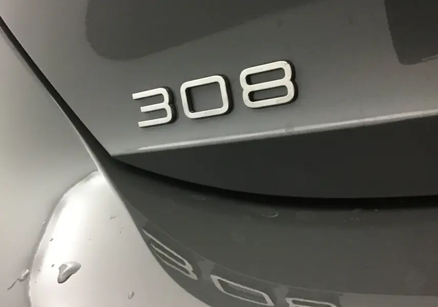 Gros plan sur l'arrière gris Sellenium d'une Peugeot 308 avec le logo 308 en relief visible.