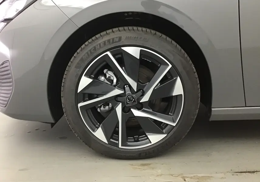 Gros plan sur la roue avant gauche d'une Peugeot 308 gris Sellenium avec jante alliage noire et argentée.