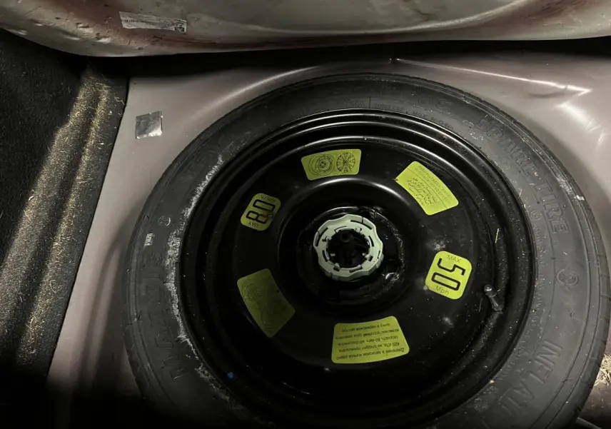 Gros plan sur la roue de secours galette noire dans le coffre violet d'une DS3 1.6 BlueHDi So Chic 2016.