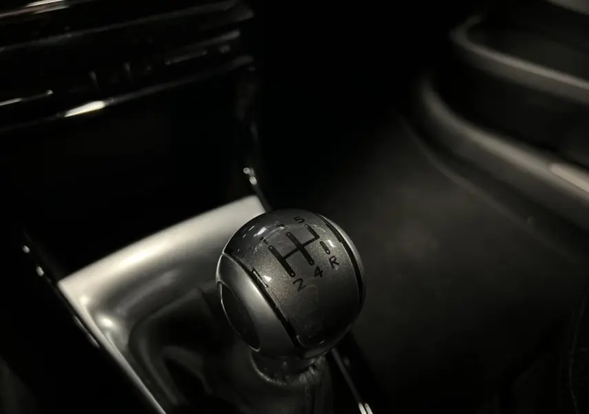 Gros plan sur le levier de vitesses manuel noir du DS3 violet, avec console centrale brillante en arrière-plan.