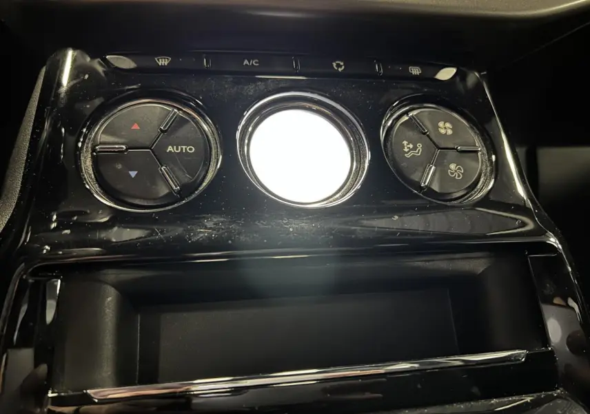 Gros plan sur les commandes de climatisation noire brillante du tableau de bord de la DS3 violet 2016.