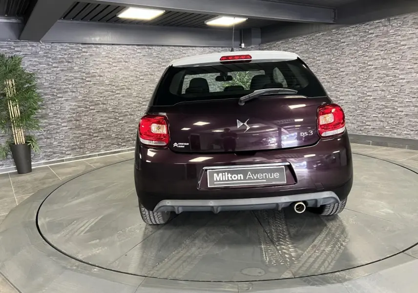 Vue arrière d'une DS3 violet foncé avec toit blanc, feux LED et canule d'échappement chromée visible en intérieur.