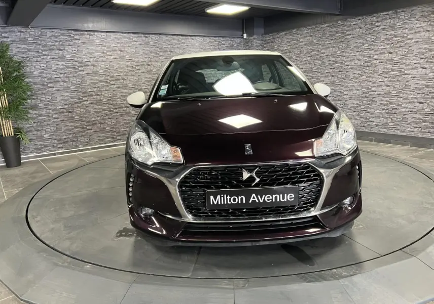 Vue frontale d'une DS3 violet foncé avec calandre chromée et plaque Milton Avenue en showroom.