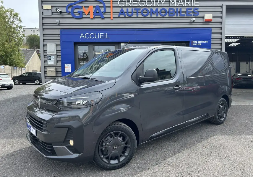 Citroën Jumpy gris titane en 3/4 avant droit, avec jantes noires et calandre moderne devant un garage GMA.