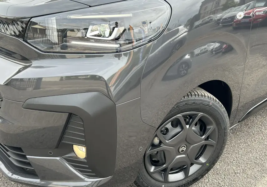 Gros plan sur l'avant droit gris titane du Citroën Jumpy 2025, mettant en valeur le phare LED et la roue au design moderne.