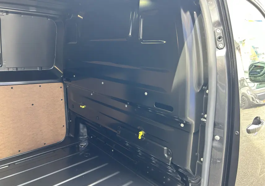 Vue intérieure côté droit de la zone de chargement du Citroën Jumpy gris titane, montrant la paroi métallique et panneau bois.