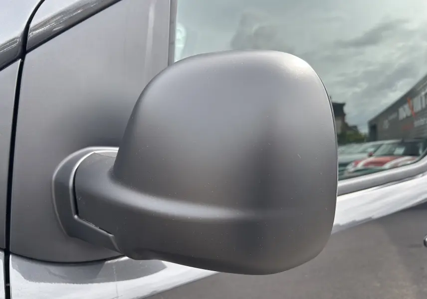 Rétroviseur côté gauche en gros plan du Citroën Jumpy gris titane sous un ciel nuageux.