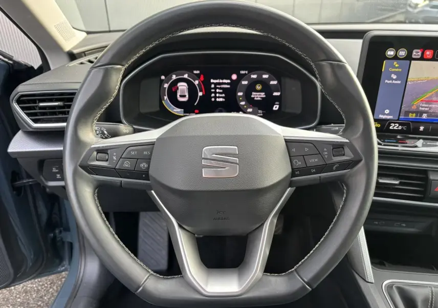 Vue rapprochée du volant cuir multifonction et du tableau de bord numérique du SEAT Leon Bleu Fjord 2025.