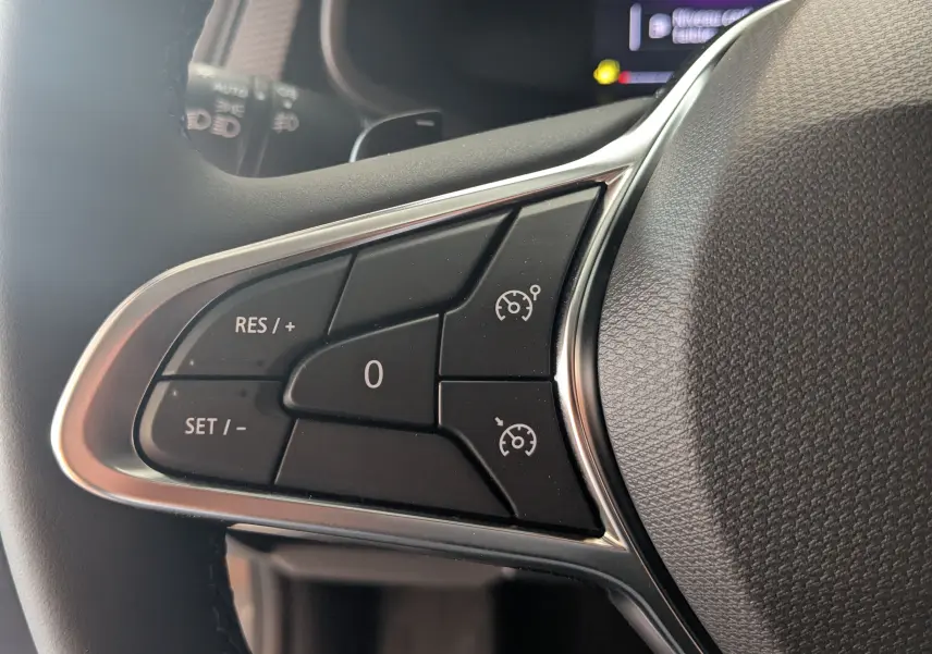 Gros plan sur les commandes de régulateur de vitesse au volant du Renault Trafic Cabine Approfondie gris Comète, côté gauche.