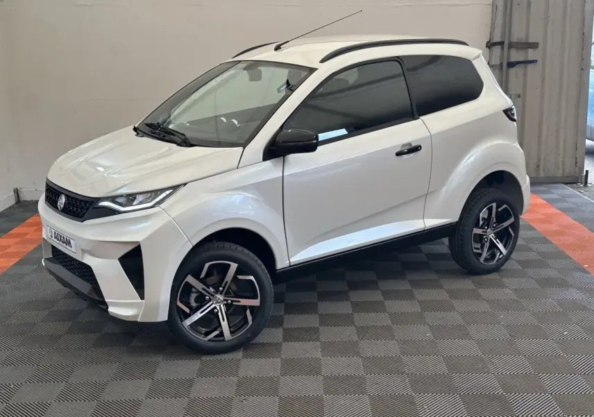 Aixam Ambition 0.5 Crossover Premium blanc, vue 3/4 avant droit, avec rétroviseur caméra côté gauche visible.