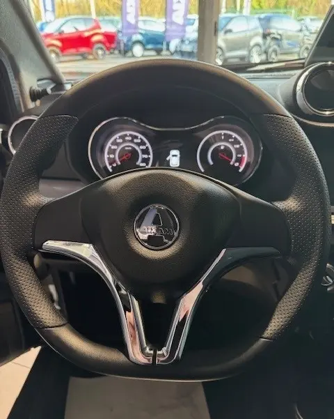 Vue intérieure centrée sur le volant noir de l'AIXAM AMBITION 0.5 CROSSOVER PREMIUM 2026, avec tableau de bord éclairé.
