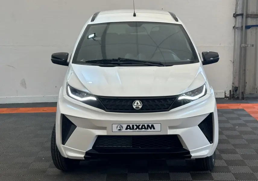 Vue frontale d'une Aixam Ambition 0.5 Crossover Premium blanche avec calandre noire et rétroviseurs caméra côté gauche.