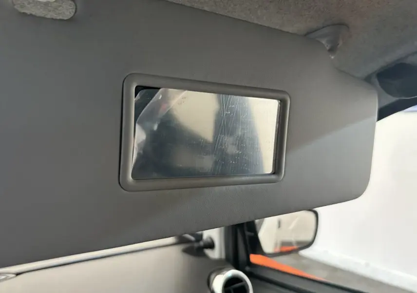 Miroir de courtoisie sur pare-soleil côté conducteur dans l’habitacle d’une Aixam Ambition blanc, vue intérieure rapprochée.