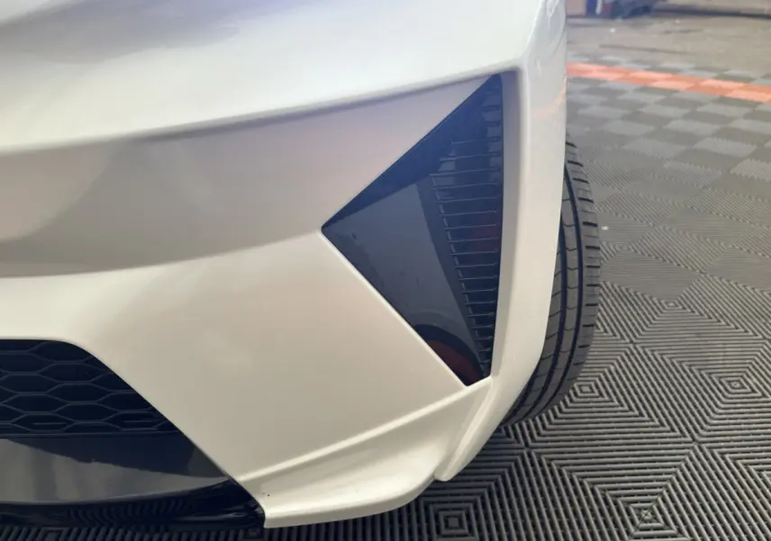 Gros plan sur l’angle avant droit blanc de l’AIXAM AMBITION 0.5 CROSSOVER PREMIUM avec détail noir brillant.