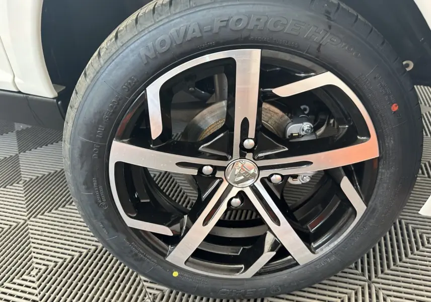 Gros plan sur la roue avant droite d’une Aixam Ambition 0.5 Crossover Premium blanche, jante noire et argentée.