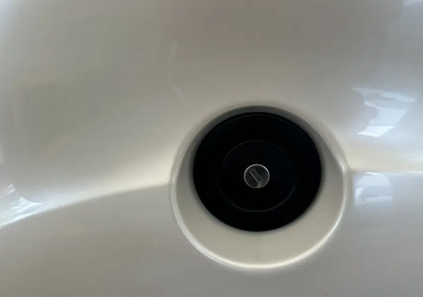 Gros plan sur la trappe de réservoir noir intégrée dans la carrosserie blanche de l'AIXAM AMBITION 0.5 CROSSOVER PREMIUM.