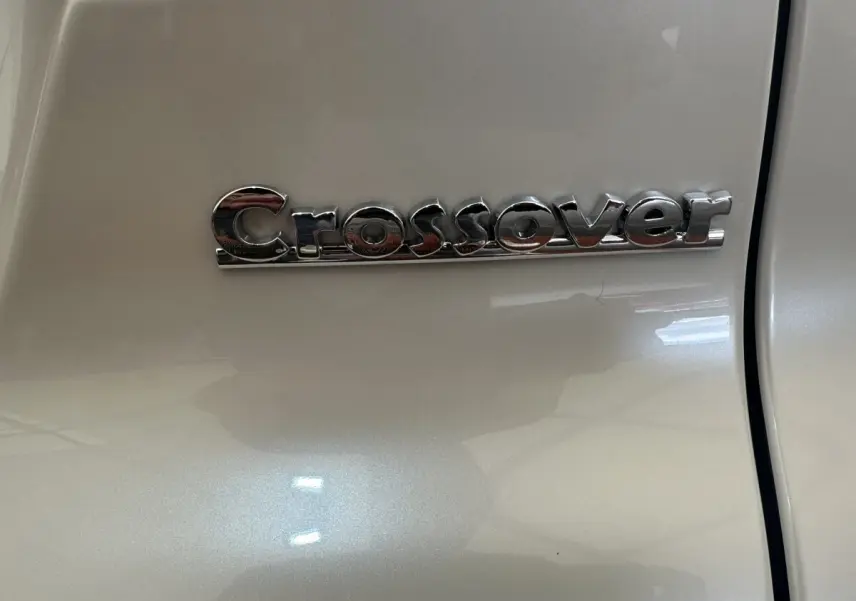 Gros plan sur l’inscription chromée "Crossover" sur la porte blanche d’une Aixam Ambition 0.5 Crossover Premium.