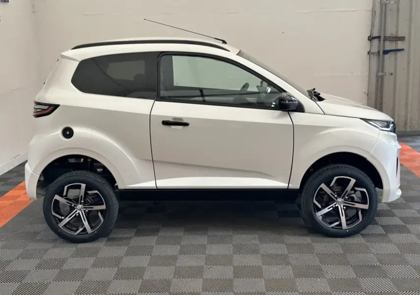 Vue de profil côté gauche d'une Aixam Ambition 0.5 Crossover Premium blanche avec rétroviseur caméra et jantes noires.