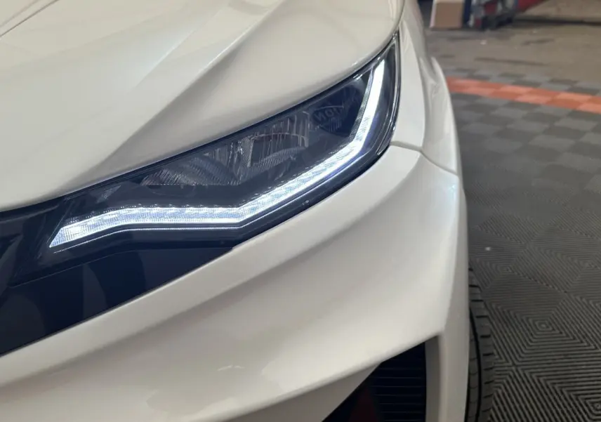 Gros plan sur le phare avant droit blanc de l'AIXAM AMBITION 0.5 CROSSOVER PREMIUM avec éclairage LED distinctif.