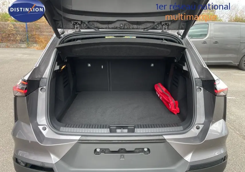Coffre ouvert vu de l'arrière d'une Renault Symbioz gris cassiopée métal, avec un kit de secours rouge à droite.