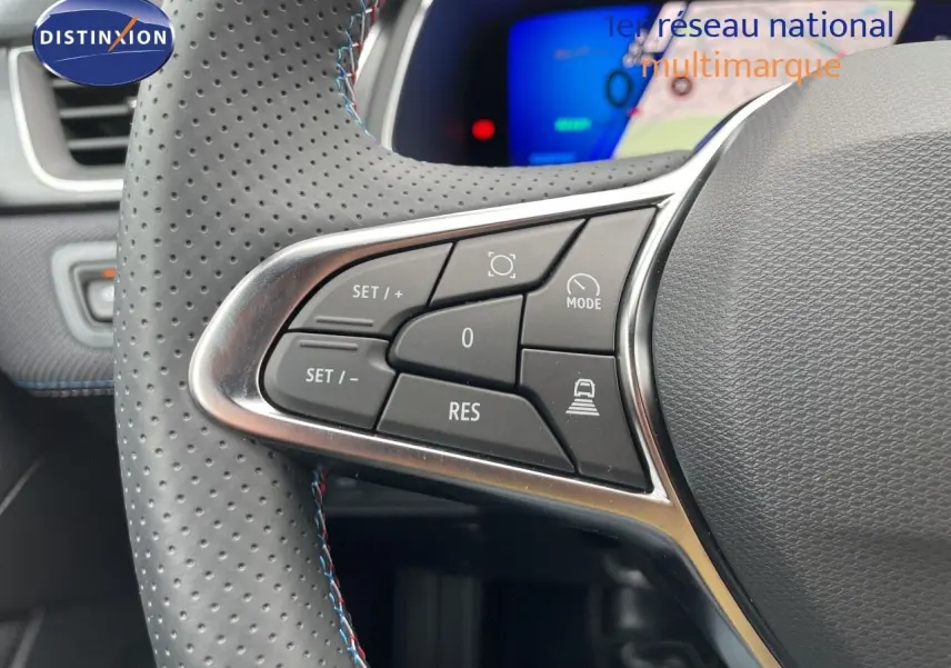 Gros plan sur les commandes à gauche du volant perforé gris du Renault Symbioz 2026, avec tableau de bord numérique en arrière-plan.