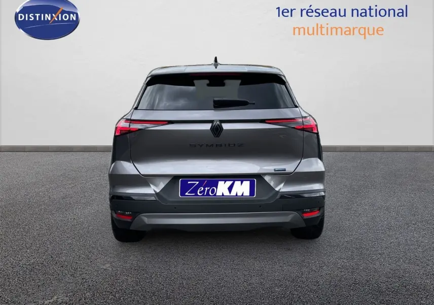 Vue arrière d'une Renault Symbioz gris cassiopée métal, avec feux arrière fins et plaque Zero KM visible.