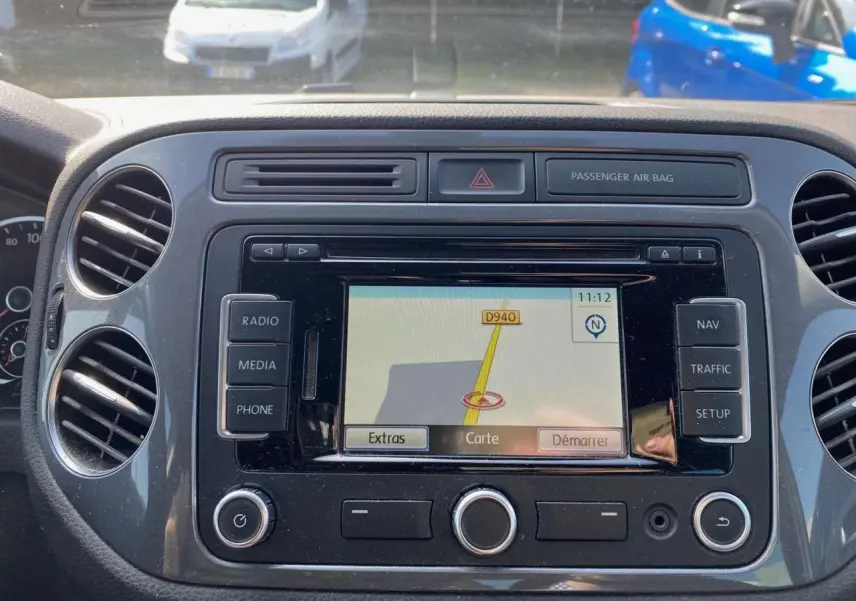 Vue rapprochée du tableau de bord du Volkswagen Tiguan blanc 2014 avec écran de navigation allumé.