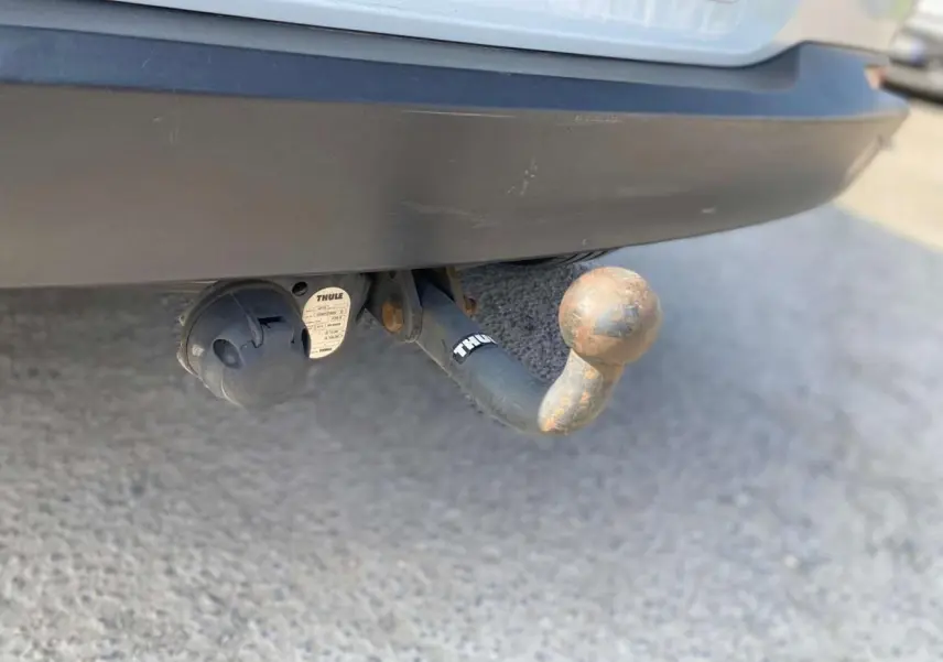 Gros plan sur l'attelage arrière rouillé du Volkswagen Tiguan blanc de 2014 avec prise électrique intégrée.