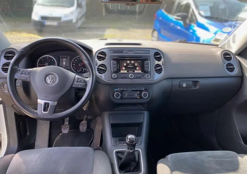 Vue intérieure du tableau de bord et volant cuir multifonction du Volkswagen Tiguan blanc avec boîte manuelle.