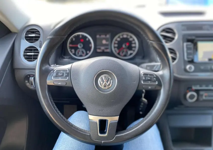 Vue centrée sur le volant cuir multifonction d'un Volkswagen Tiguan 2014, tableau de bord et commandes visibles.
