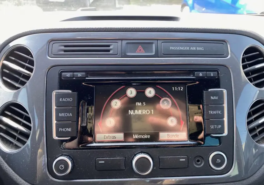 Vue rapprochée de l'écran multimédia central du Volkswagen Tiguan 2014 avec commandes radio et navigation visibles.