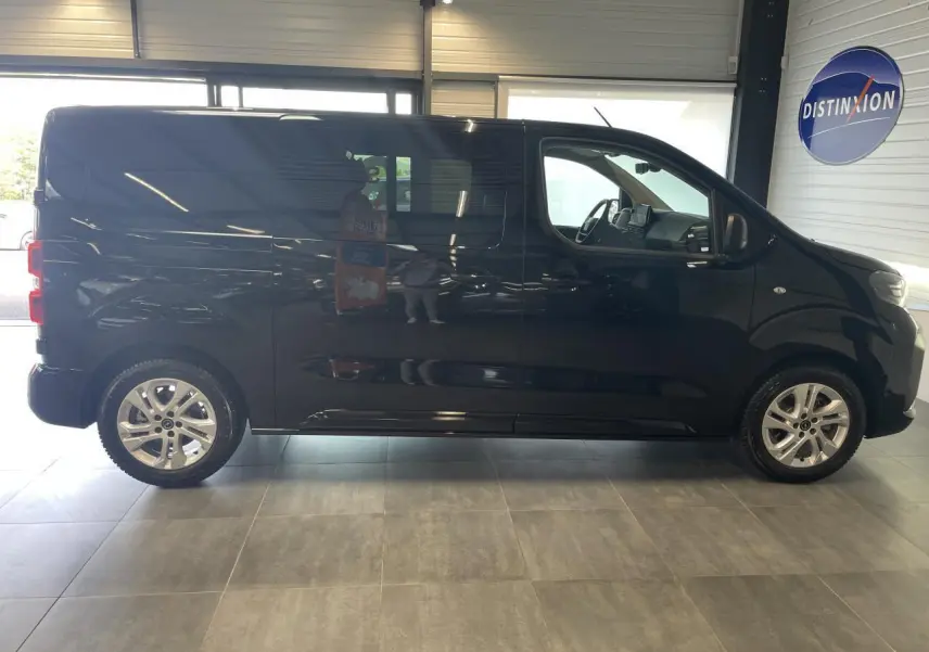 Profil droit d'un Opel Vivaro noir carbone double cabine 2025 avec jantes alliage et vitres surteintées en showroom.