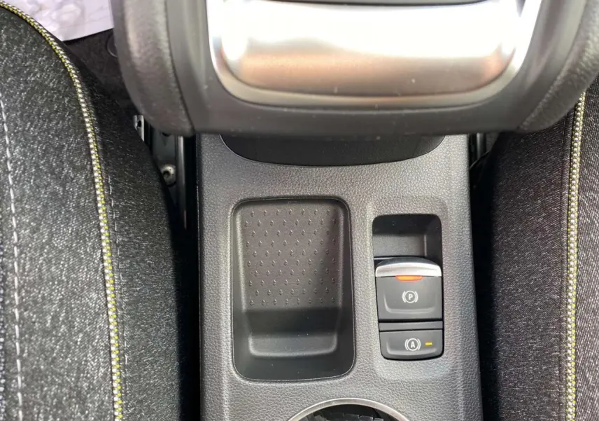 Gros plan sur la console centrale du Renault Captur Techno 2025, montrant le frein à main électrique et un espace de rangement.