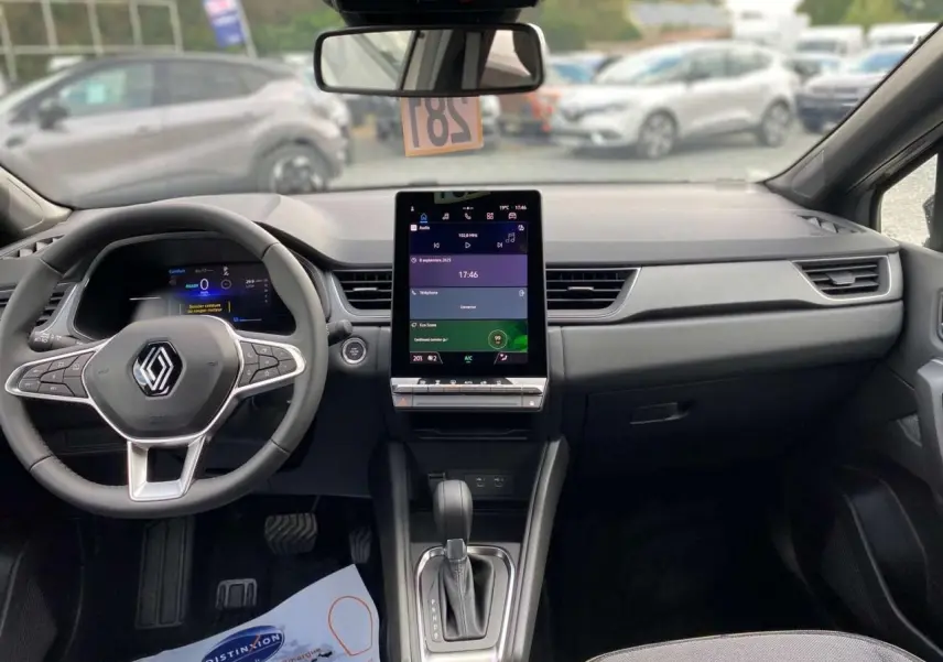 Vue intérieure frontale du tableau de bord du Renault Captur 2025 avec écran tactile vertical et volant multifonction.