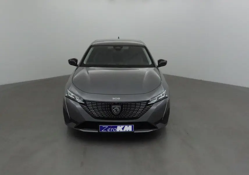 Peugeot 308 gris Sellenium vue de face dans un studio, avec calandre noire et phares LED fins.