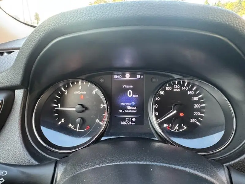 Tableau de bord noir du Nissan X-TRAIL 2018 avec compte-tours, compteur de vitesse et écran multifonction central.