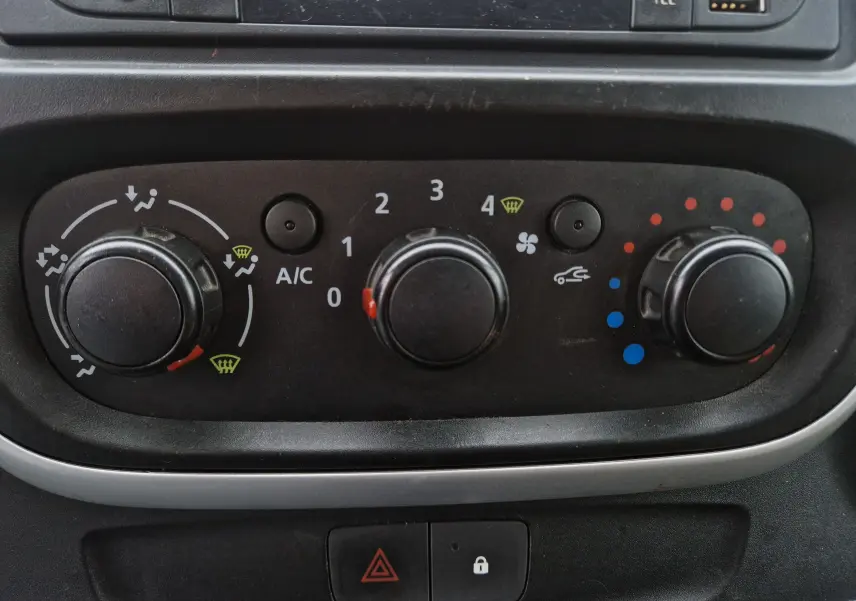 Panneau de commande de climatisation noir dans un Renault Trafic Fourgon blanc, vue rapprochée du tableau de bord.