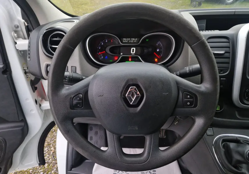 Vue intérieure centrée sur le volant noir du Renault Trafic blanc, tableau de bord et compteurs visibles derrière.