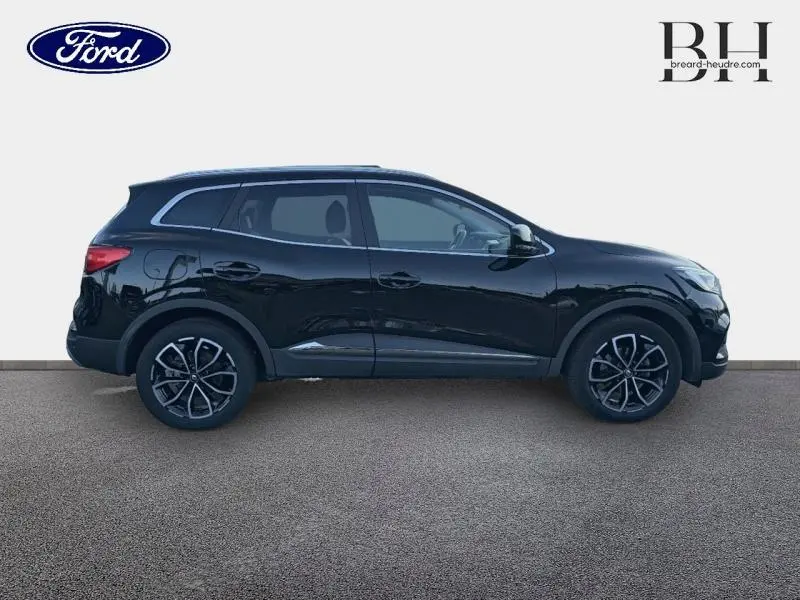 Profil droit du Renault Kadjar 1.3 TCe 140ch noir étoilé avec jantes alliage et barres de toit visibles.