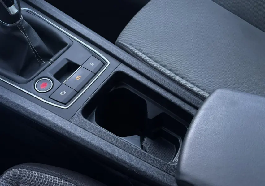 Gros plan sur la console centrale noire du SEAT LEON ST 2.0 TDI 115 Style, avec boîte manuelle et accoudoir en cuir.