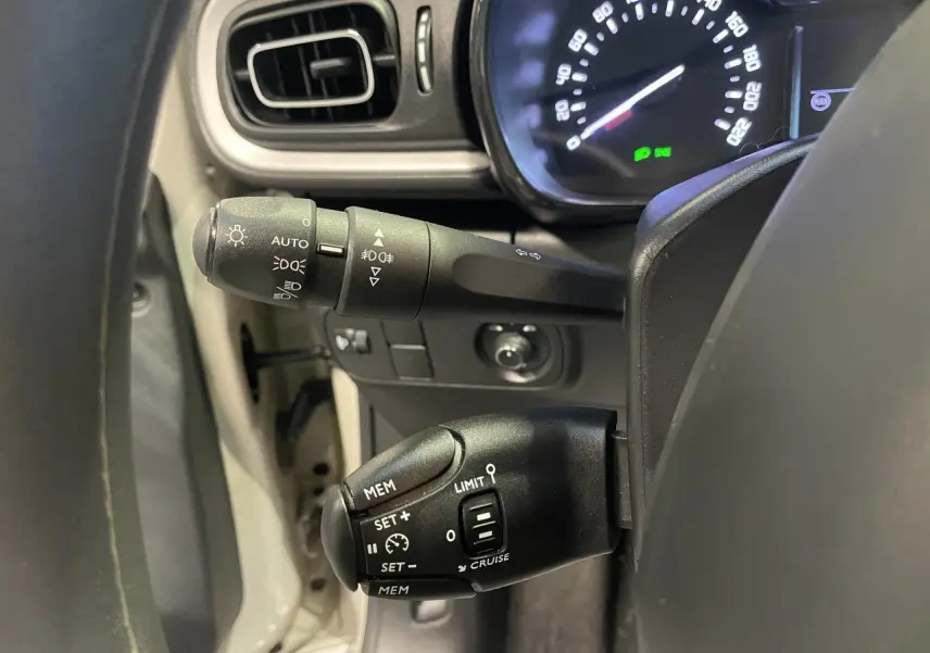 Gros plan sur la commande de régulateur de vitesse et les commandes d’éclairage du tableau de bord d’une Citroën C3 beige clair 2024.