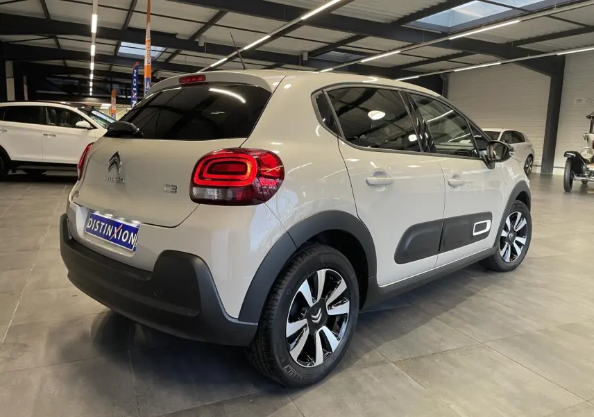 Vue 3/4 arrière droite d'une Citroën C3 beige clair avec Airbump noirs et jantes alliage diamantées en showroom.