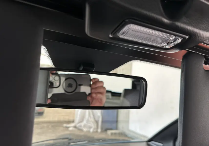 Vue intérieure centrée sur le rétroviseur intérieur de l'AIXAM Ambition 0.5 City Pack 2026, avec reflet du conducteur.