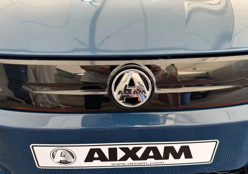 Gros plan avant sur la calandre bleue de l'AIXAM AMBITION 0.5 CITY PACK avec logo central et plaque constructeur.