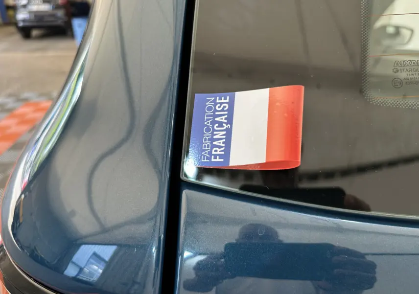 Gros plan sur la partie arrière bleue d'une Aixam Ambition 0.5 City Pack avec autocollant "Fabrication Française" sur la vitre.