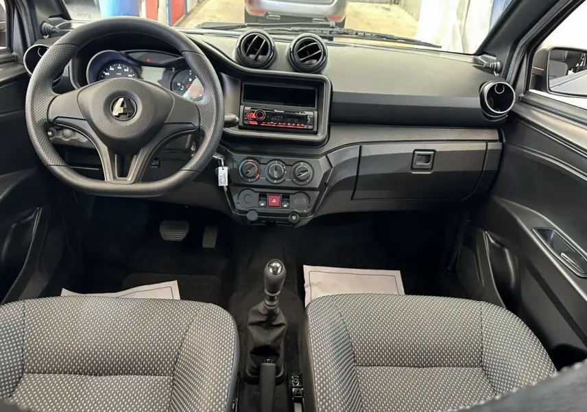 Vue intérieure avant de l'AIXAM AMBITION 0.5 CITY PACK 2026, tableau de bord noir avec volant et sièges gris à motifs.