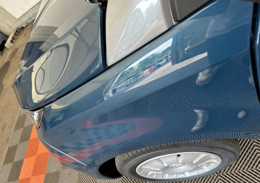 Gros plan sur l’aile avant gauche bleue de l’AIXAM AMBITION 0.5 CITY PACK 2026 avec rétroviseur caméra côté conducteur.