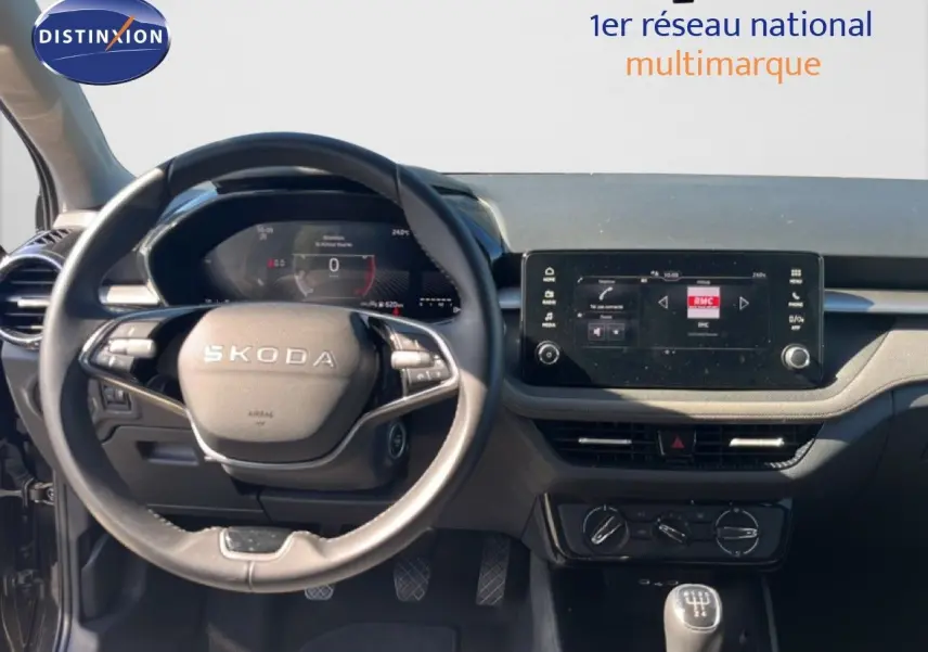 Vue intérieure centrée sur le volant SKODA et le tableau de bord avec écran tactile, ambiance sobre en noir.