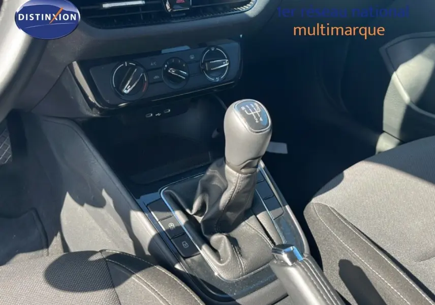 Gros plan sur la console centrale de la Skoda Fabia noire, mettant en valeur le levier de vitesse manuel et les commandes de climatisation.