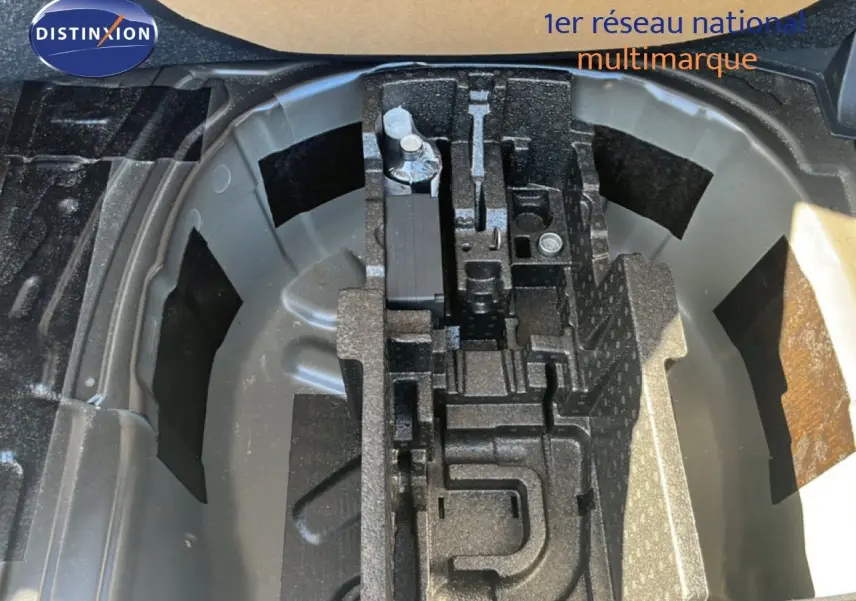 Vue en plongée sur le compartiment de roue de secours d'une Skoda Fabia 2025 noir magique métal, avec outils de bord rangés.